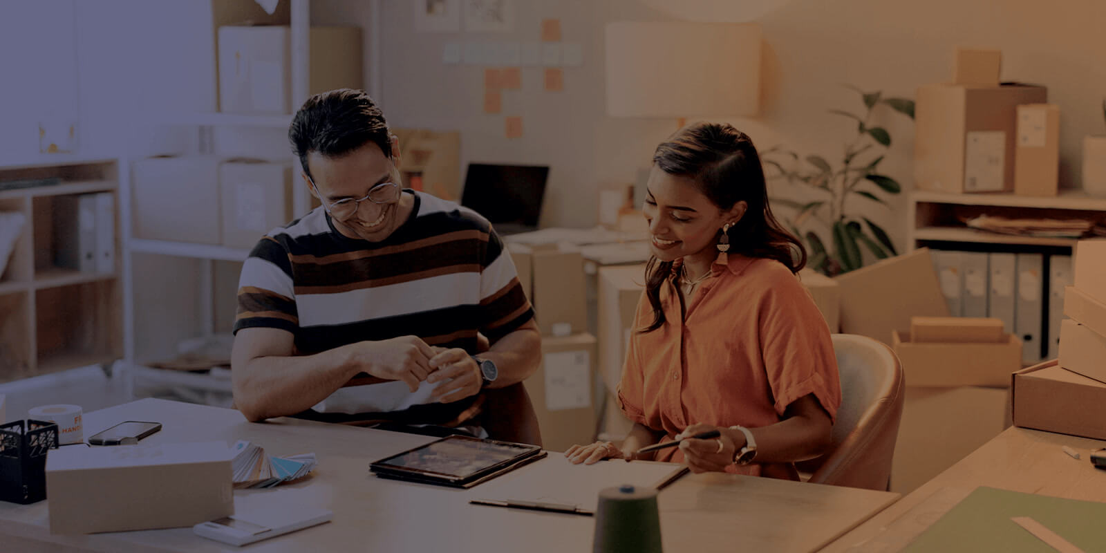 Small business owners sitting in a workspace looking at a tablet.