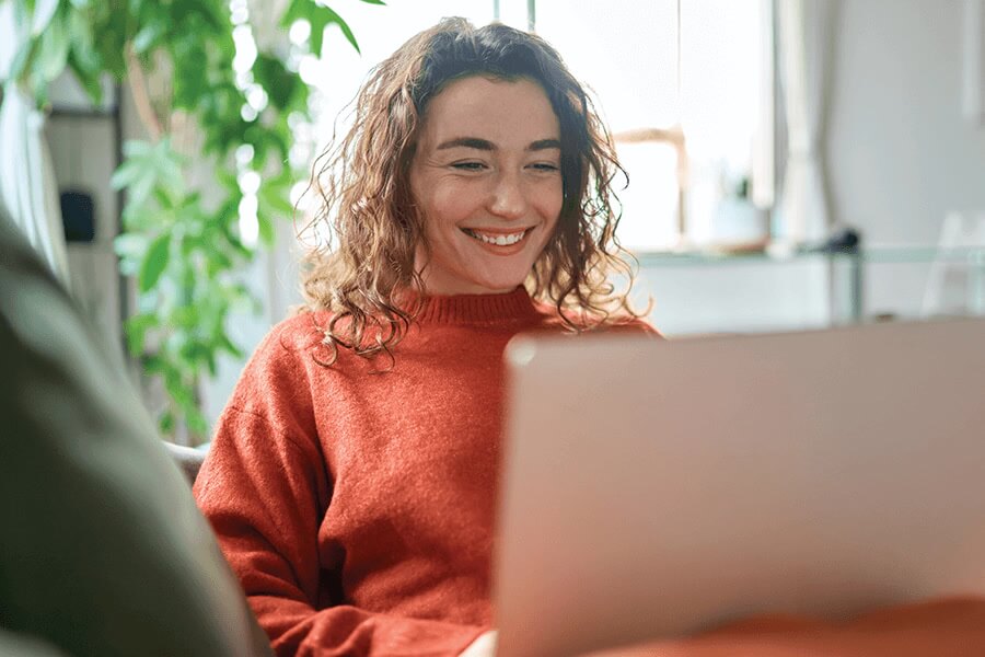 Woman sits and works on her computer at home.